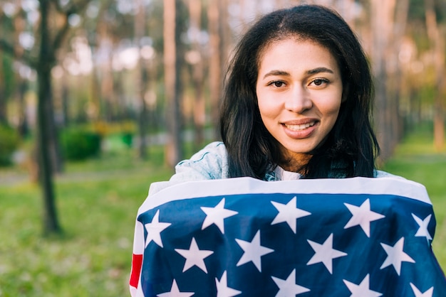 Foto gratuita femmina etnica avvolta nella bandiera americana