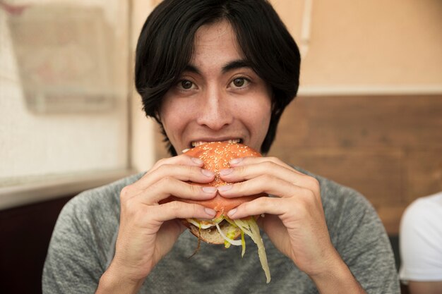 民族の男性がハンバーガーを食べるとカメラ目線