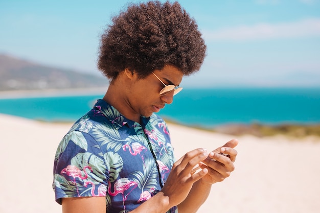 Бесплатное фото Этнические мужчины, глядя на смартфон на песчаном пляже