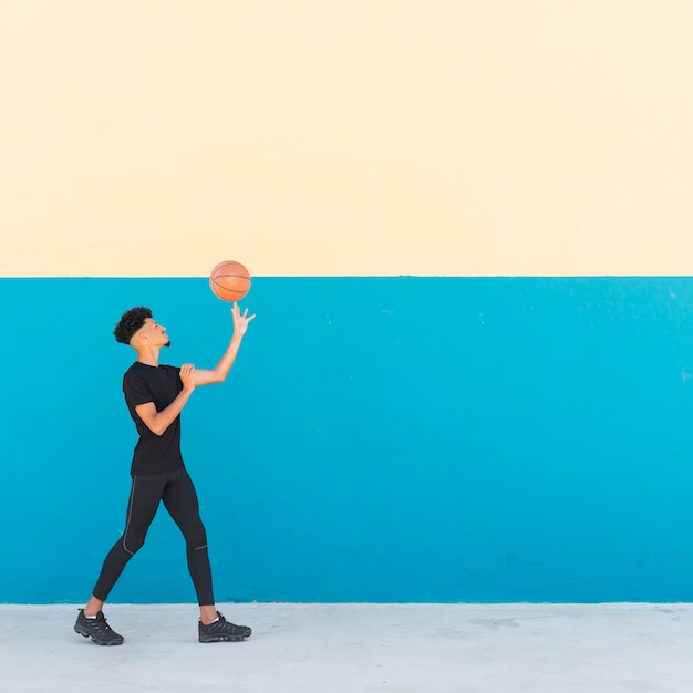 Ethnic male spinning basketball on finger