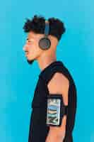 Бесплатное фото Этнический спортсмен, используя наушники с телефоном в повязке