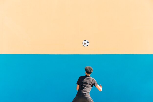 Ethnic sportsman with curly hair tossing football