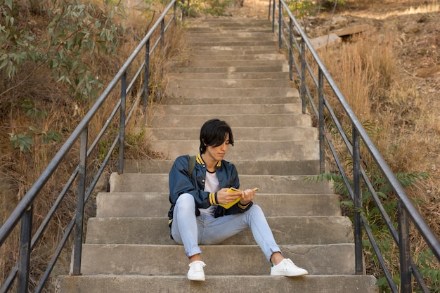 Ethnic teenager sitting with book on stairs