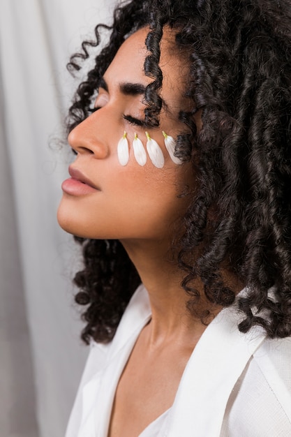 Ethnic woman with petals on face