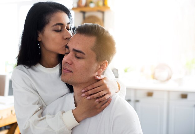 Ethnic young woman kissing in temple boyfriend