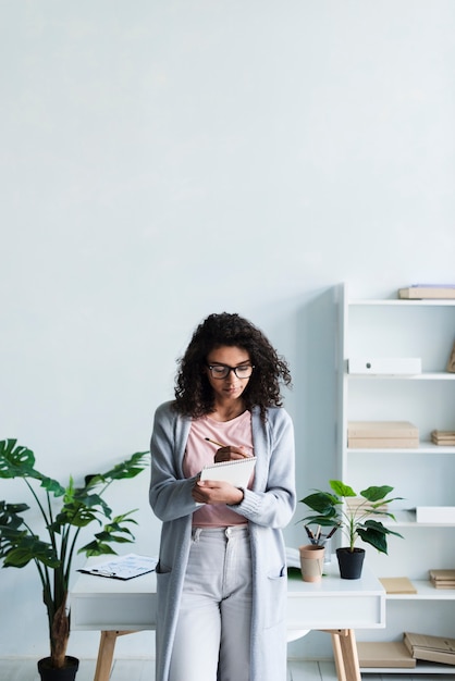 Free photo ethnic young woman writing on clipboard