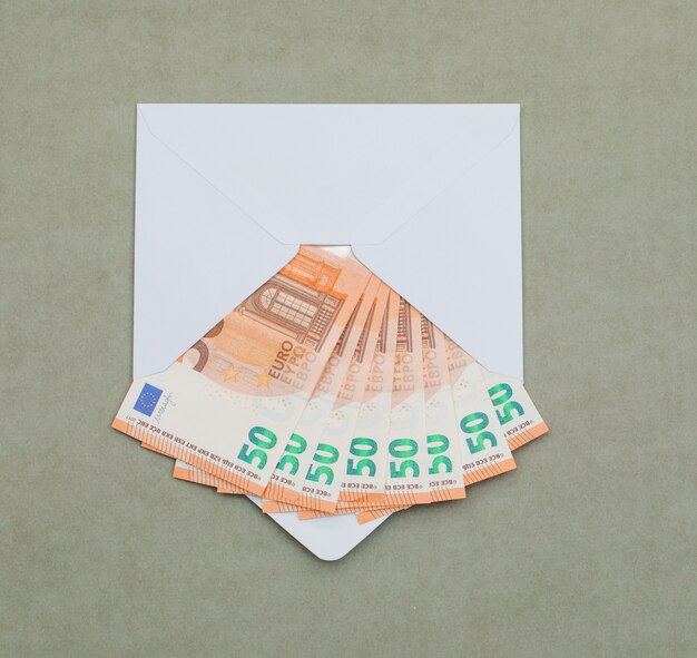 евро счета в конверте на зеленовато-серый стол.