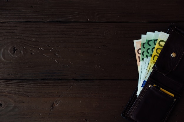 Euro cash in brown wallet on wooden background 