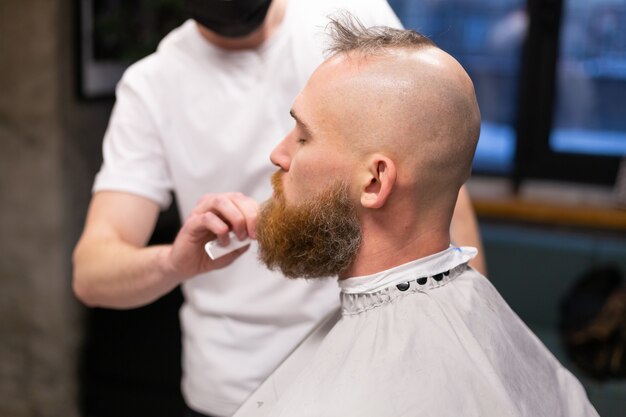 European brutal man with a beard cut in a barbershop