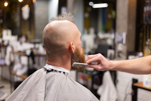 European brutal man with a beard cut in a barbershop