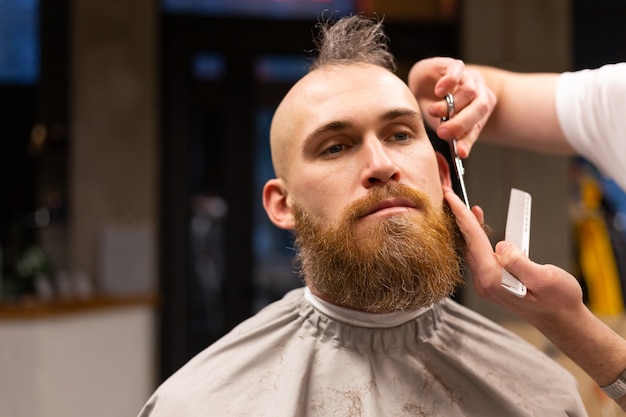 European brutal man with a beard cut in a barbershop