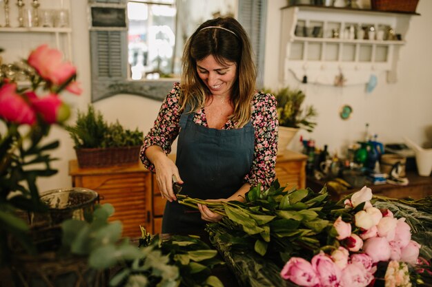 European female florist with a green apron making flower arrangements