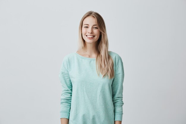 European female model with long blonde hair, wears light blue sweater