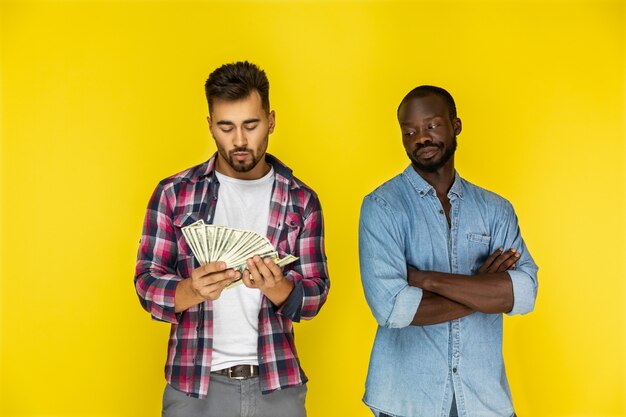 European guy is counting money and afroamerican guy is looking at him