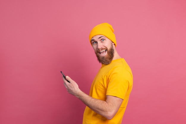 European handsome happy cheerful man with mobile phone smiling on pink
