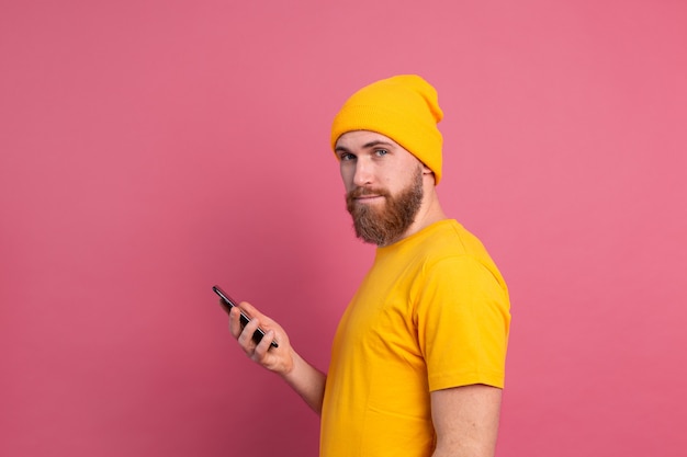 European handsome happy cheerful man with mobile phone smiling on pink