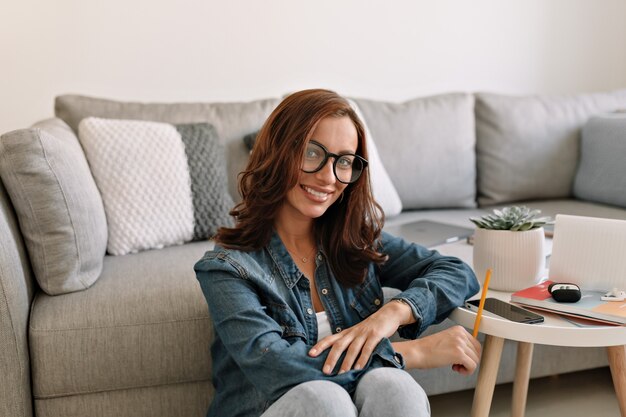 European happy adorable lady with curly hair sitting in modern office and working