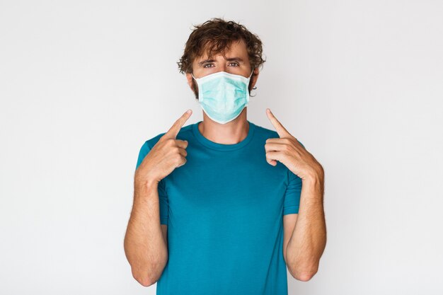 European man in protective mask pointing to himself