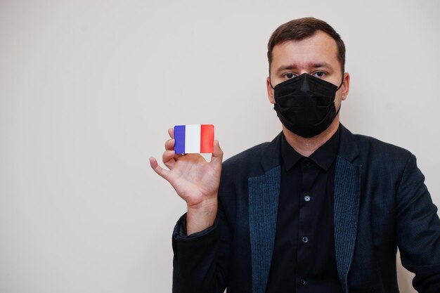 유럽 남성은 검은색 정장을 입고 얼굴 마스크를 보호하며 유럽 코로나바이러스 코비드 국가 개념에 격리된 프랑스 국기 카드를 들고 있습니다.