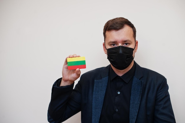 European man wear black formal and protect face mask hold Lithuania flag card isolated on white background Europe coronavirus Covid country concept