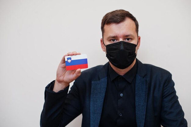 European man wear black formal and protect face mask hold Slovenia flag card isolated on white background Europe coronavirus Covid country concept