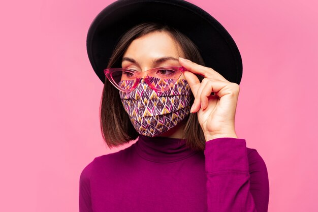 European model dressed protective stylish face mask. Wearing black hat and sunglasses.