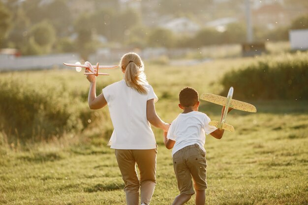 European mother and african son. Family in a summer park. People plays with plane.