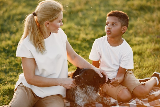 European mother and african son. Family in a summer park. People sitting on the blanket.