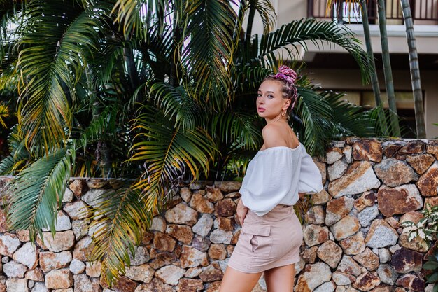 European stylish woman with pink colorful summer braids in beige skirt and white blouse