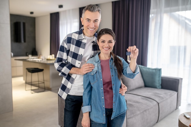 Free photo event smiling man hugging happy wife showing new keys at camera