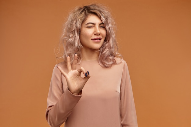 everything in under control. isolated shot of adorable confident young european woman with stylish hairdo and nose ring connecting thumb and fore finger