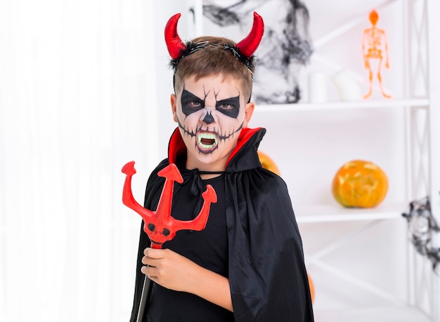 Evil kid with face painted holding a trident