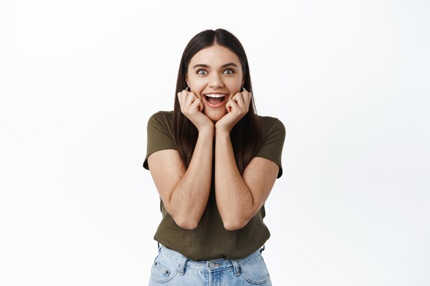 Excited and amazed young woman staring at front with astonishment and anticipation, watching something cool happening, react to awesome news