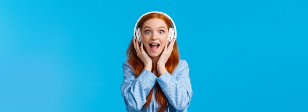 Excited and amused attractive caucasian redhead woman in pyjama screaming from fascination and amaze