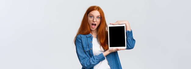 Excited and amused attractive redhead teenage girl making design creative project on device screen s