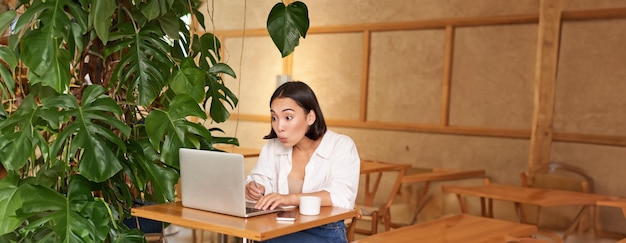 Free photo excited asian girl found something online looking at laptop screen with surprised amazed face