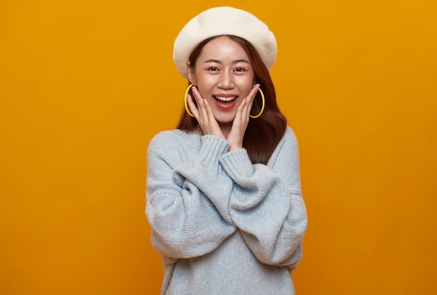 Excited asian teen woman shocked surprised isolated on studio yellow background