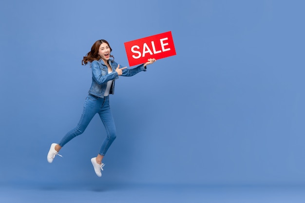 Excited asian woman jumping with red sale sign