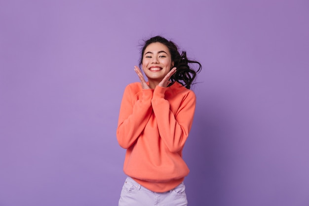 Excited asian woman with ponytail laughing to camera. Studio shot of happy chinese woman expressing positive emotions.