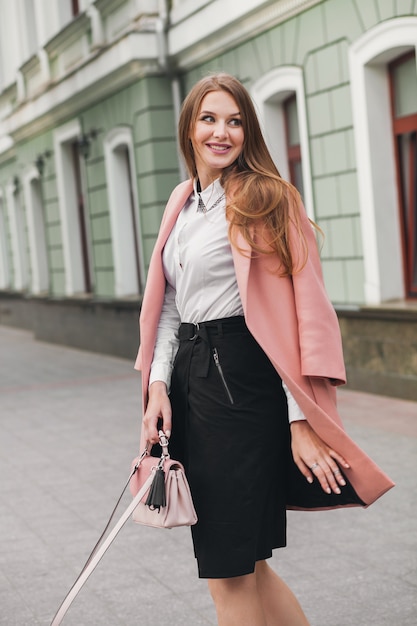 분홍색 코트에 도시 거리를 걷고 흥분된 매력적인 세련된 웃는 여자