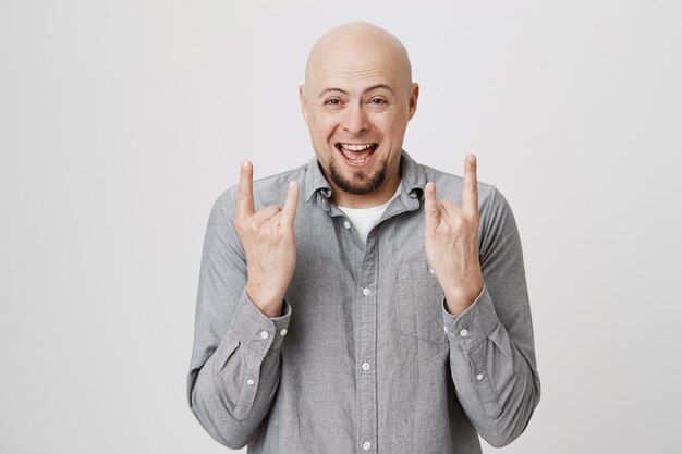 Excited bald guy smiling, showing heavy metal gesture