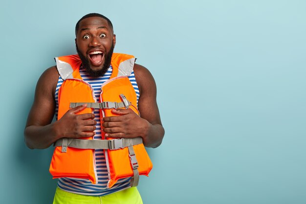 Excited bearded muscular man posing with beach items