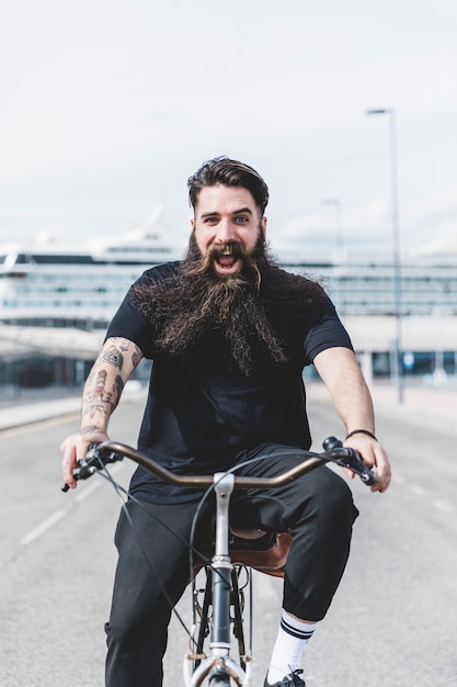 Free photo excited bearded young man enjoying riding the bicycle