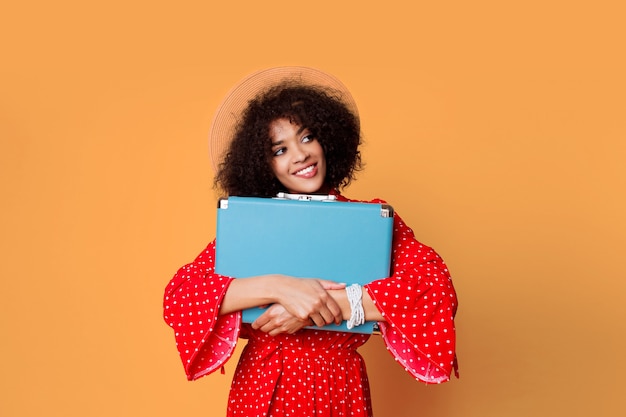 Free photo excited  black girl with african hairstyle holding cute blue suitcase.