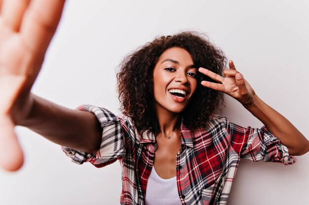 Excited black girl with short hairstyle having fun on white. enthusiastic pretty woman in red shirt.