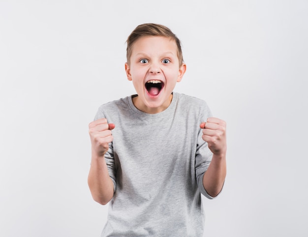 Excited boy clenching his fist standing against white backdrop