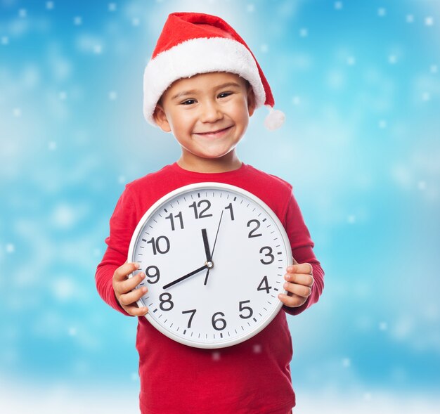 Excited boy showing a white clock