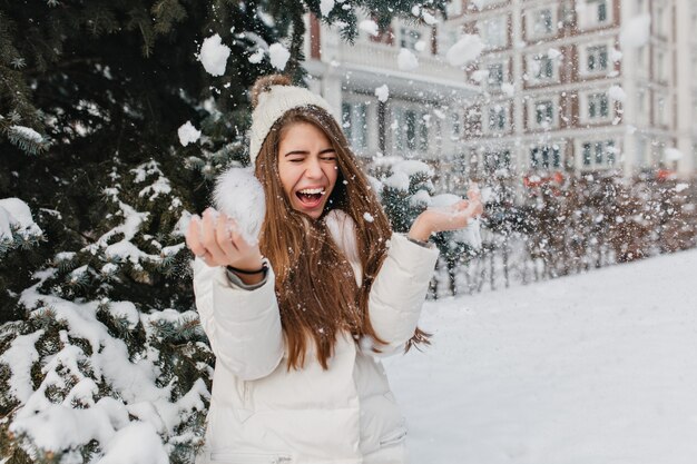 Excited brightful image of joyful amazing pretty winter woman having fun with snow outdoor on street. Happy moments, play with snowflakes, enjoying, positive emotions.