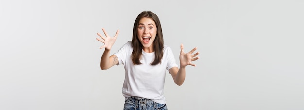 Free photo excited brunette girl smiling amazed and raising hands to catch something