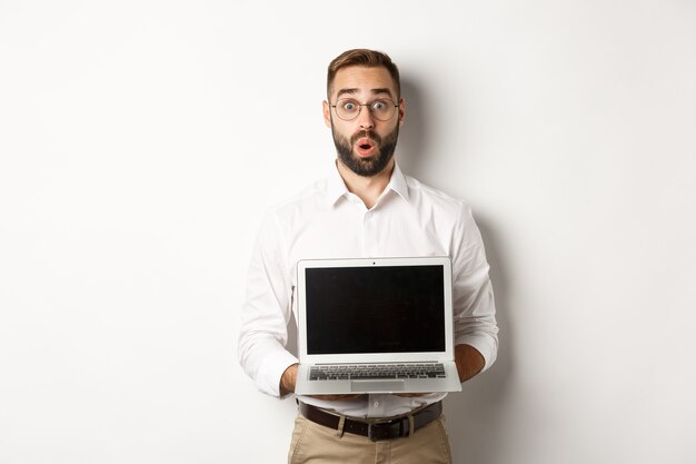 Excited businessman showing something on laptop screen, standing happy  